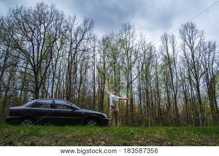 yang man stratching near car after long road on road aside