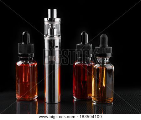 Electronic cigarette and bottles with assorted vape liquid on black background