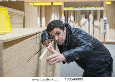 male customer choosing flakeboard or Oriented strand board OSB in the supermarket. Buying Construction and building material. Man is measuring sterling board