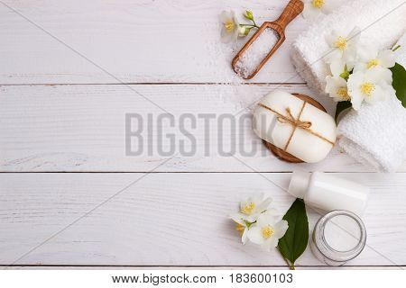 Spa setting and health care items, jasmin aromatic soap, body oil, bath salt, milk, massage stones and towels, on wooden board