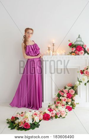 Lovely girl in beautiful dress posing in studio. Spring flowers and a romantic mood.