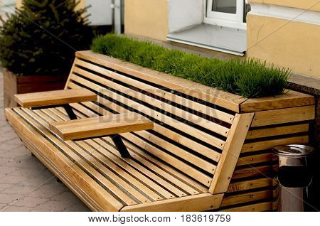 Modern wooden bench with armrest table and decorated with lawn grass