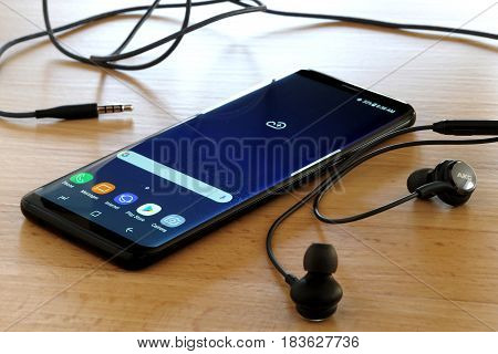 Koszalin, Poland - 27 April, 2017: Black Samsung Galaxy S8 on wooden table. Samsung S8 are new generation smartphone from Samsung. The Samsung S8 is smart phone with multi touch screen
