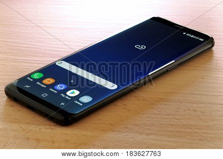 Koszalin, Poland - 27 April, 2017: Black Samsung Galaxy S8 on wooden table. Samsung S8 are new generation smartphone from Samsung. The Samsung S8 is smart phone with multi touch screen