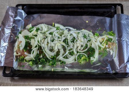 Fillet Is Fresher Than Fish In Seasoning Under Greens And Onions On A Foil On A Black Background