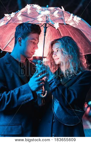 Portrait of a guy and a girl under an umbrella on a night street