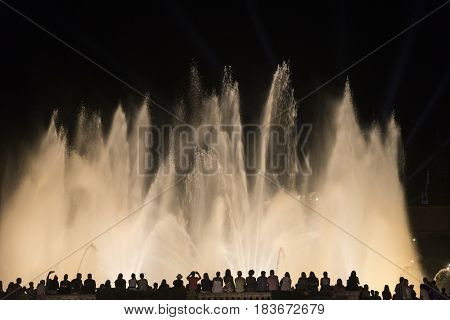 BARCELONA, SPAIN - JULY 29, 2016: Barcelona (Catalunya Spain): the Magic Fountain (Fuente Magica Font Magica) of Montjuic with plays of colorful lights at evening and people in silhouette watching at the show