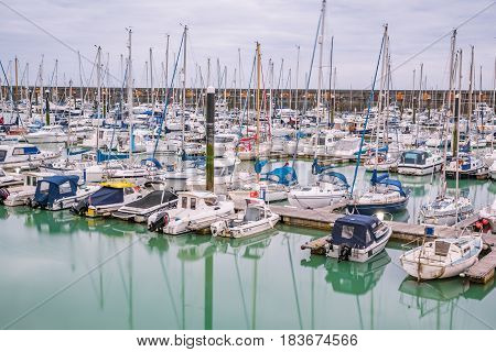 Boats yachts and fishing boats moored at Brighton Marina docs on a cloudy day.