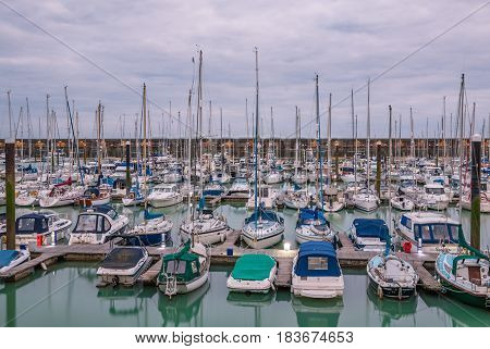 Boats yachts and fishing boats moored at Brighton Marina docs on a cloudy day.