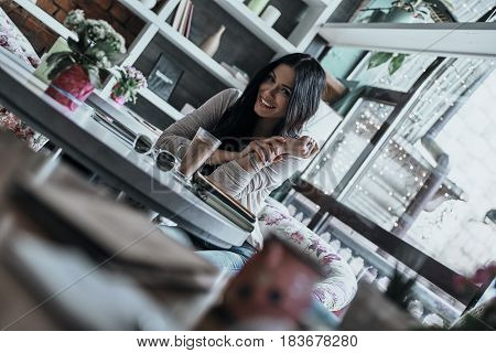 Carefree time in cafe. Attractive young woman looking at camera with a smile while sitting in restaurant