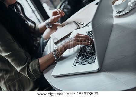 Catch up on some work. Close-up of woman using laptop while sitting at her working place