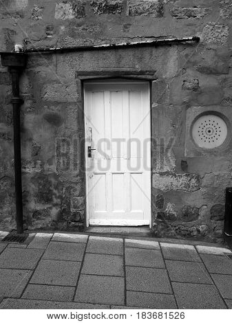 Old weathered wall with white door on sloping street