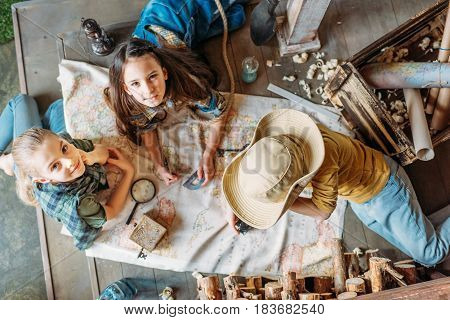 Overhead View Of Little Kids Travelers Sitting Together On Porch With Map