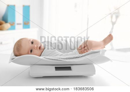 Cute little baby lying on scales in clinic