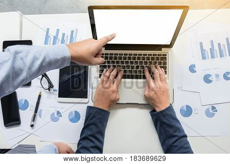 Image of two young businessmen working with laptop tablet smartphone and financial document data graph on table in office.