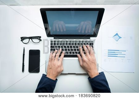 Young businessman working with laptop and smart-phone on his desk in office.