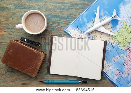 Travel , trip vacation, tourism mockup - close up note book, suitcase, toy airplane and touristic map on wooden table. Empty space you can place your text or information.