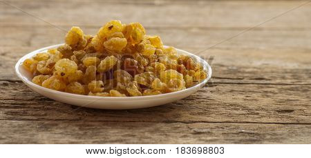 dried grapes close up on white plate on wooden background