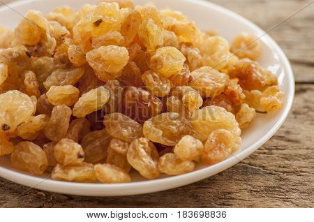 dried grapes close up on white plate on wooden background