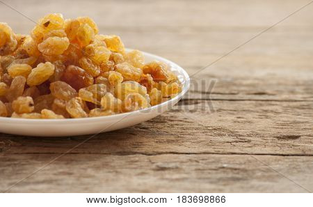 dried grapes close up on white plate on wooden background