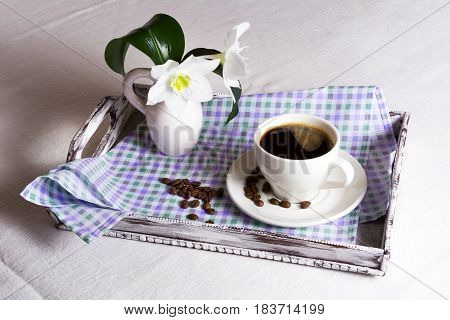 Cup of morning coffee with white flowers on rustic wooden serving tray. Tender love concept.