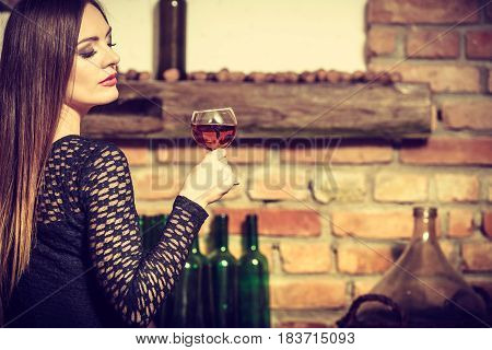 Elegant beauty lady long hair full make up wearing black dress tasting wine in rural cottage interior celler