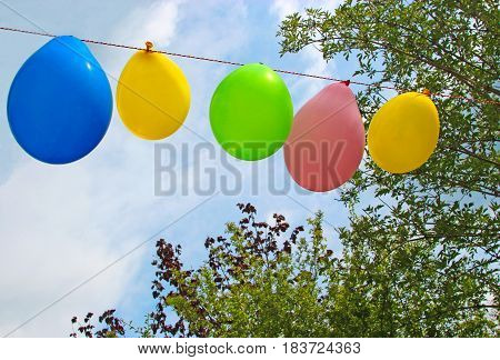 ready for the garden party, string of balloons in front of sky and trees