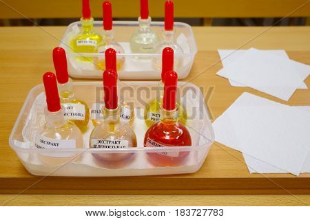 Test tubes with solutions on table, paper napkins, Text translation - sea buckthorn oil, almond oil, green tea extract, oatmeal extract