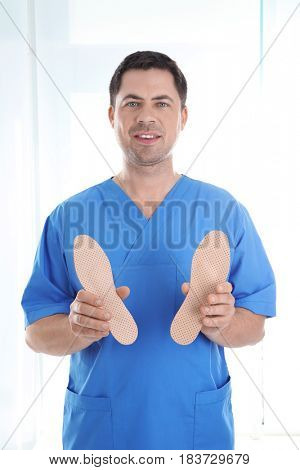 Male orthopedist with insoles on white background