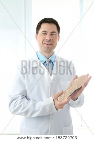 Male orthopedist with insole on white background