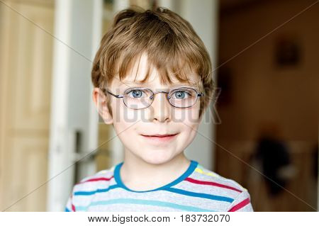 Portrait of little cute school kid boy with glasses and colorful school uniform fashion clothes. Child smiling and looking at the camera. Boy with missing front teeth