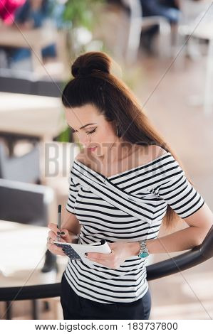 Portrait of young business woman in the office making notes about her subordinates
