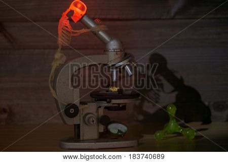 concept image that show process of scientific discovery with sceleton looking at microscope. braind is boiling and turning red