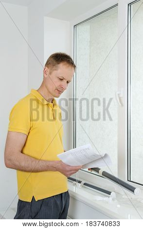 Man is reading instruction for the installation of window blind.