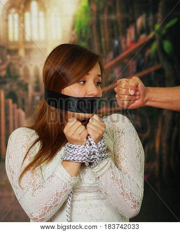 Male fist against terrified kidnapped young woman in the background