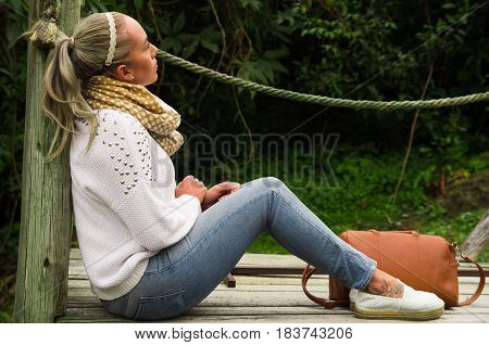 Beautiful young blond contemplative woman in a sitting enjoying nature