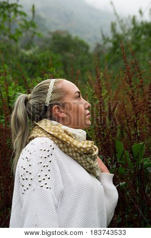 Pretty young reflective woman standing looking up in a mountain