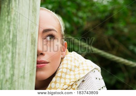 Close up shot if young blond girl sitting in a walking wooden bridge looking peaceful