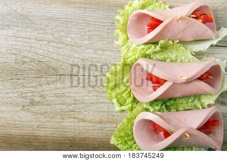 Roll of homemade sausage with vegetables on a wooden background. Space for text
