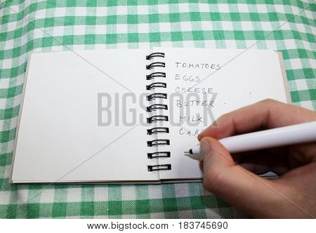 Hand with pencil writing shopping grocery list
