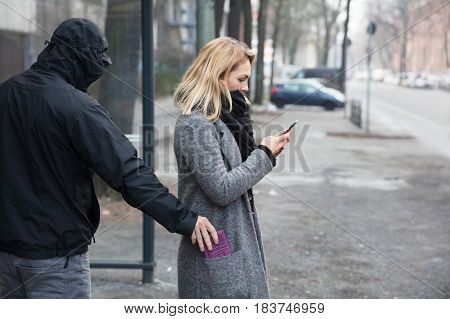 Man In A Hood Stealing Purse From Woman's Coat Pocket On Street