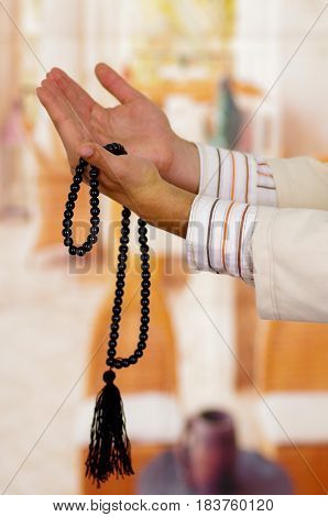 Arabian guy praying to his god and holding a masbaha.
