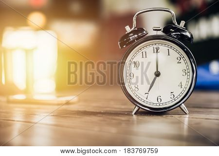 7 O'clock Time Retro Clock On Wood Table With Sun Light Background