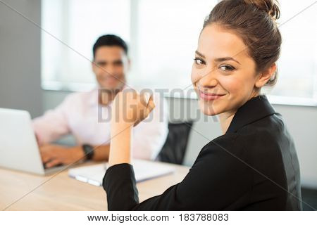 Portrait of smiling businesswoman sitting at table with colleague in background