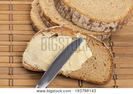 Close up a knife spreading butter on bread