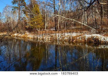 scenery around autumn river. On the mirror-smooth water the reflections of the trees visible