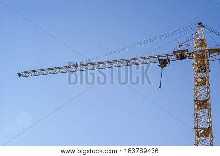 Tower crane against blue sky. yellow construction crane on a background of blue sky.