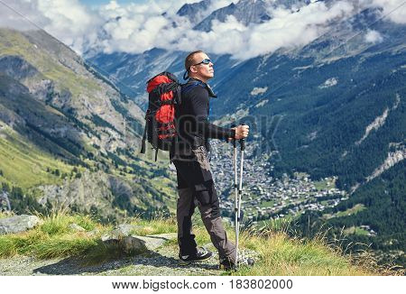 hiker on the trail in the Apls mountains. Trek near Matterhorn mount. Mountain ridge and Zermatt town on the background
