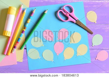 Paper card with air balloons, scissors, glue stick, paper air balloons, colored paper, pencils on a table. Air day or birthday card. Fun art activity for preschool and kindergarten. Easy kids crafts