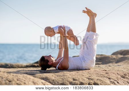 A Mother And A Son Are Doing Yoga Exercises At The Seashore Of Mediterranean Sea